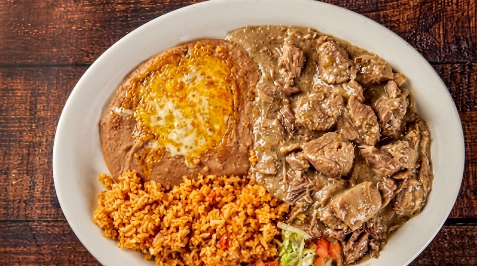 Platter with chile verde, refried beans with melted cheese, Mexican rice, and a small salad.