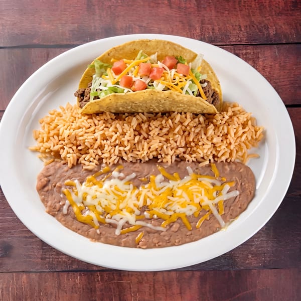 A beef taco with lettuce, cheese, and tomatoes, served with rice and refried beans.